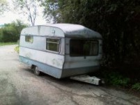 old abandoned caravan parked up against the road